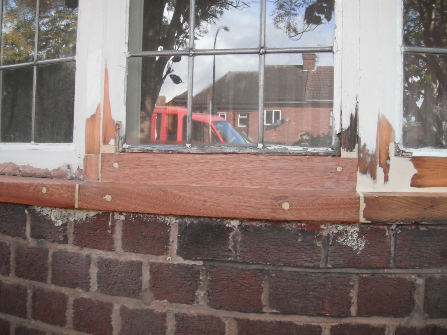 Close-up of rotten casement window sill being repaired