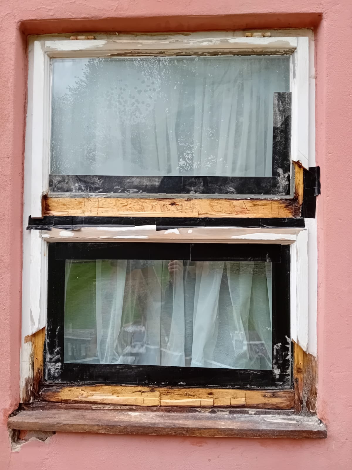 Casement window mid-restoration — frame stripped and taped ready for repair