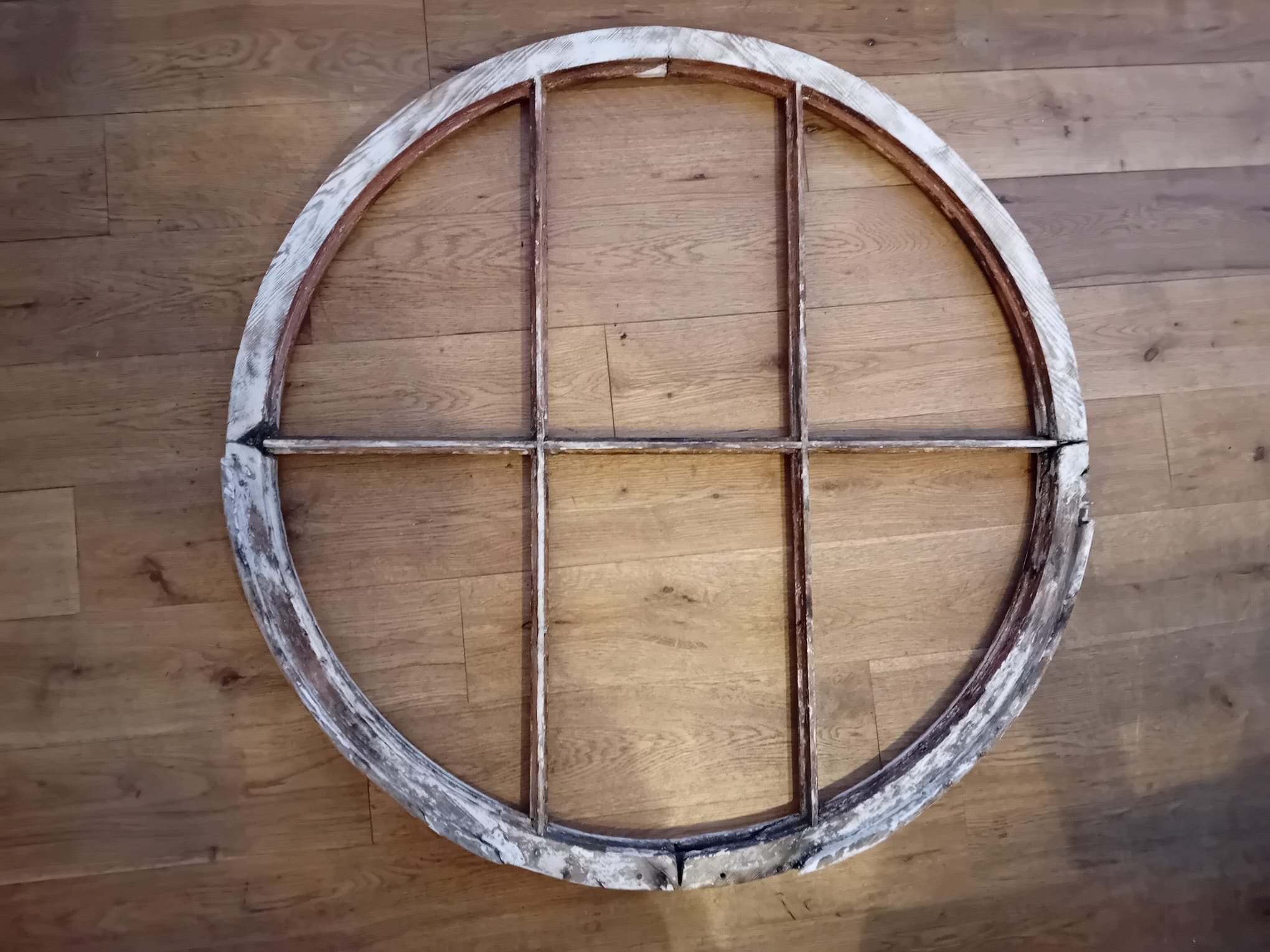 Circular window before restoration — stripped frame on workshop floor