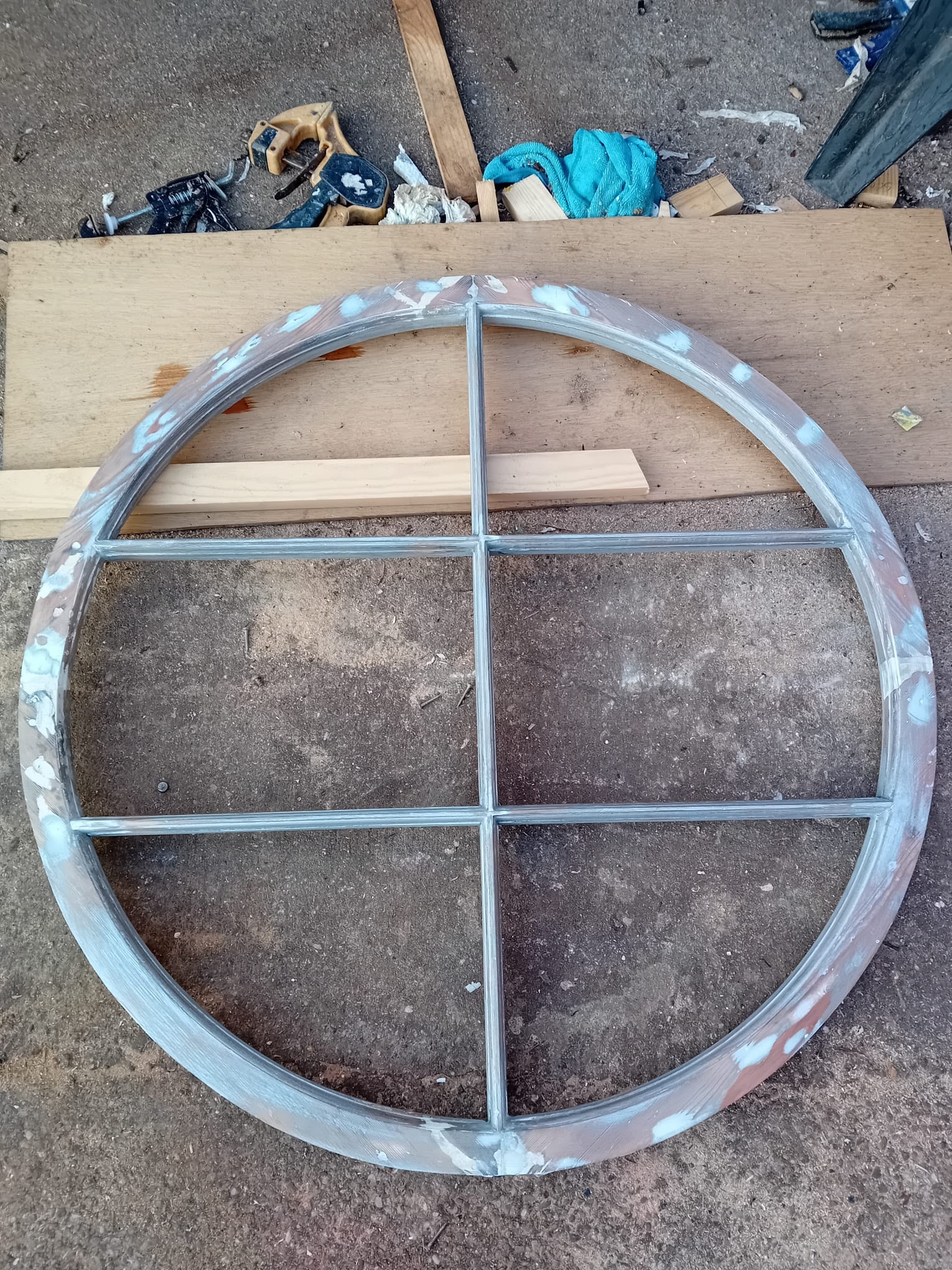 Circular window mid-restoration — primed frame in workshop